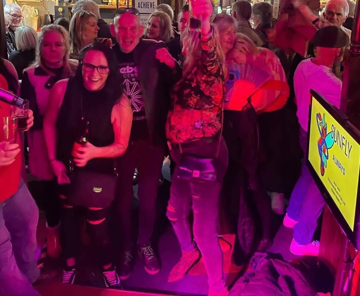 Guests enjoying a karaoke night beside a lyrics screen.