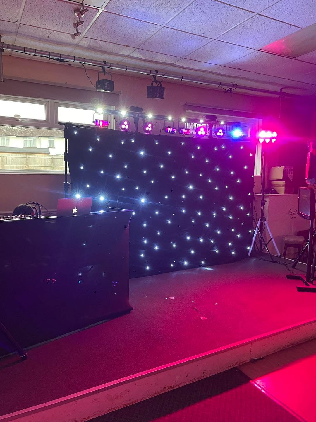 Karaoke stage setup with a starcloth backdrop and coloured lights.